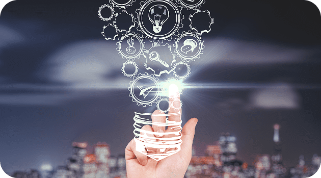 A hand holding a glowing lightbulb against a dark city skyline